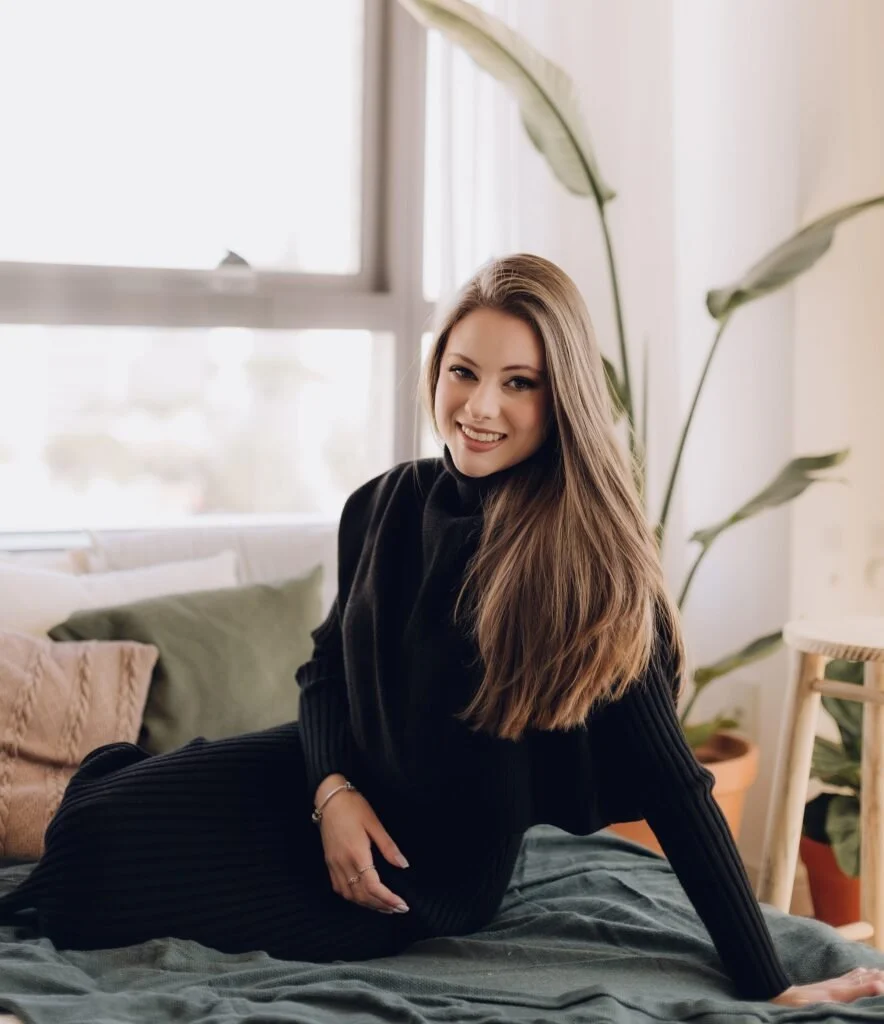 Ana Martha Massucheto sorrindo, sentada junto à janela